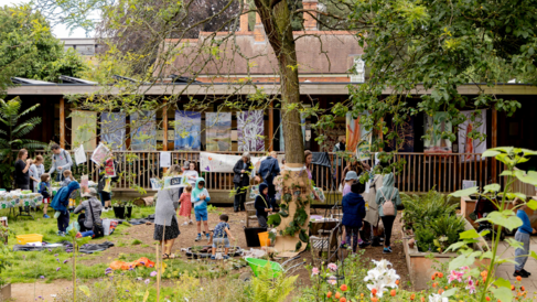 Image of children making art in the Cambridge Botanical Gardens - Wide angle shot with building in background and flowers in foreground